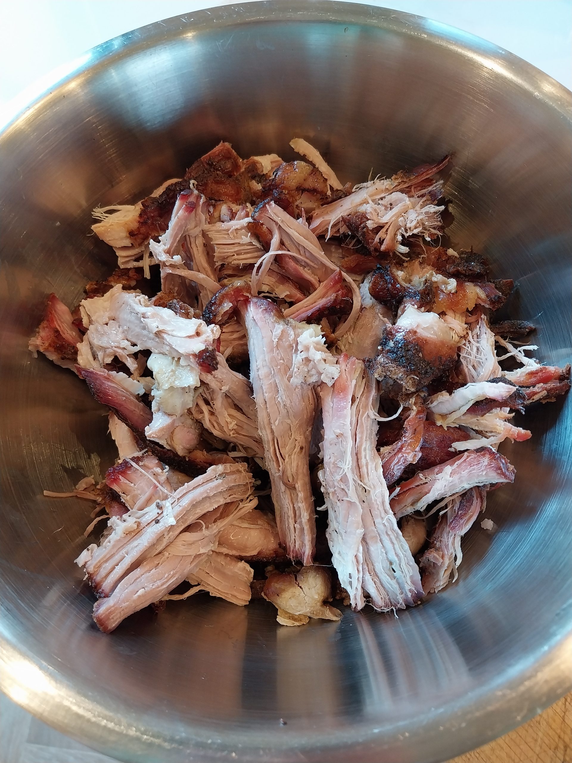 Pork shoulder after the overnight faux-cambro rest — smaller piece pulled cleanly, larger piece needed chopping rather than pulling because its collagen hadn't fully rendered before the cook was cut short.