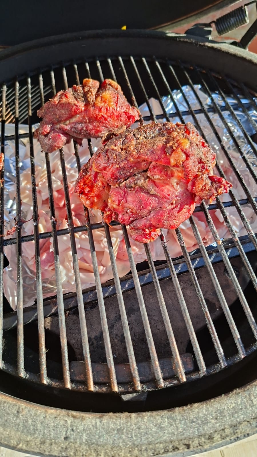 Two pieces of UK supermarket pork shoulder seasoned and on the BGE Large grate mid-cook at 110°C indirect, showing the natural two-piece state most UK BBQ recipes don't acknowledge.