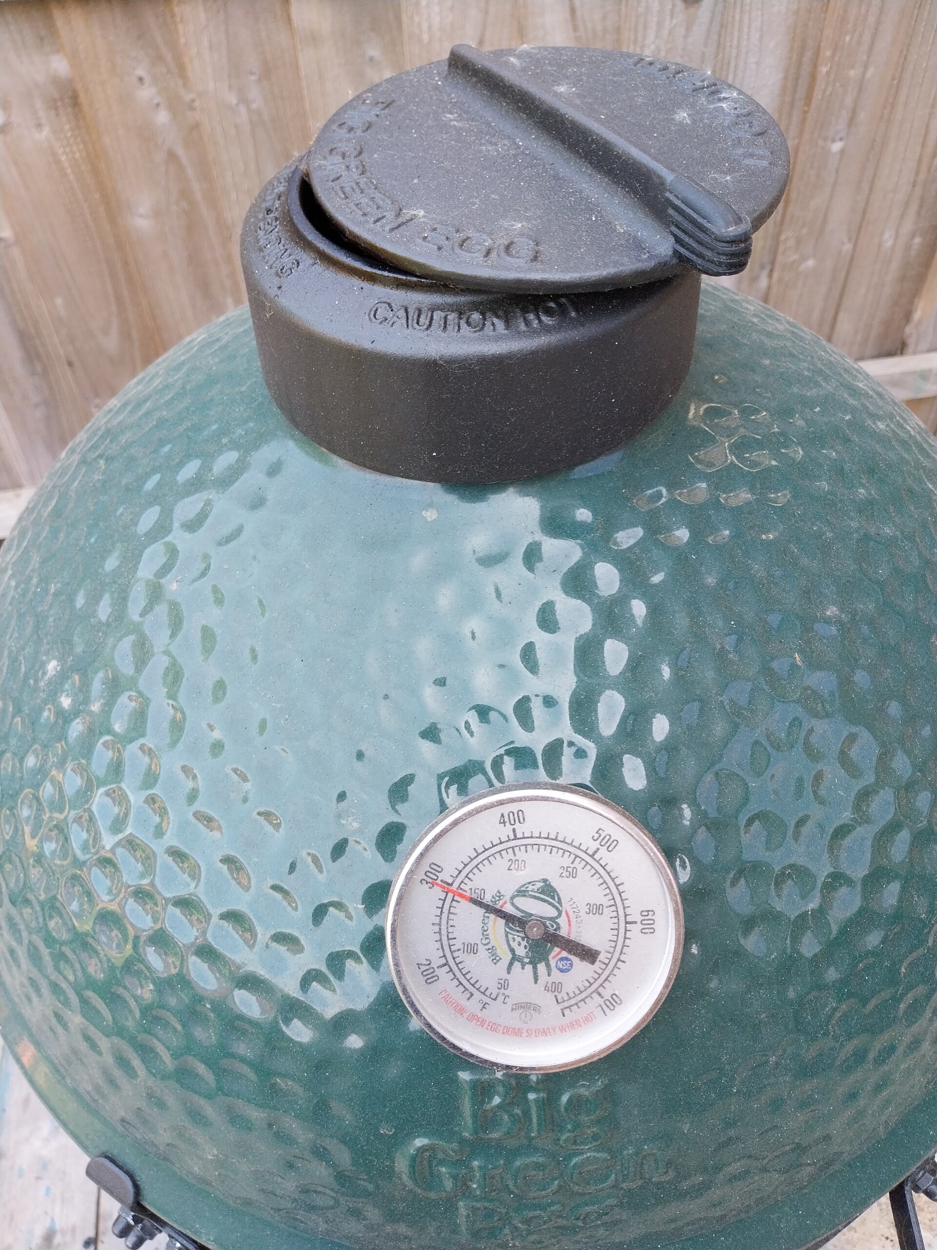 Cast-iron daisy-wheel top vent on a Big Green Egg Large with green hammered glaze visible — close-up showing build detail