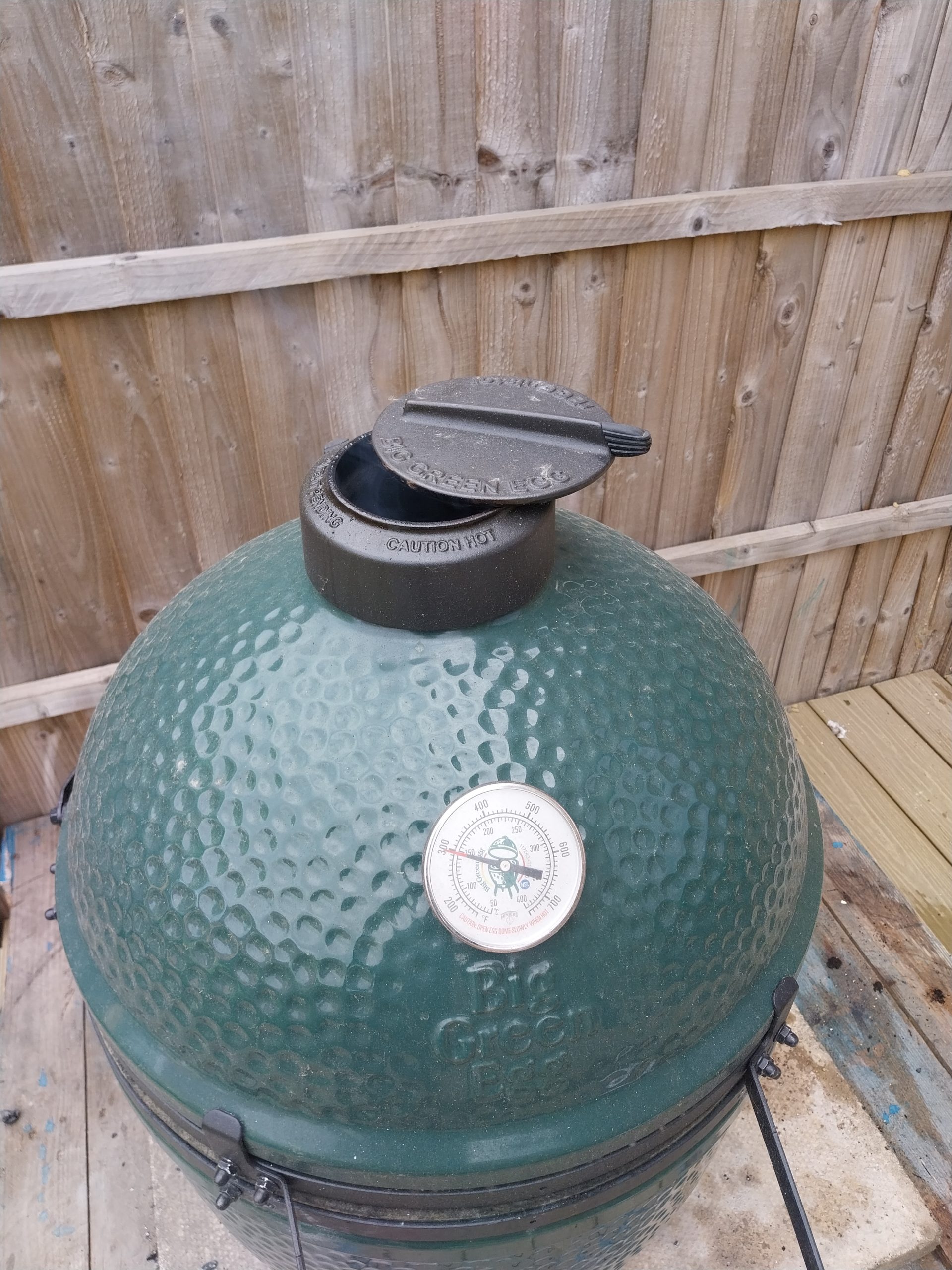 Big Green Egg Large in cook mode, dome closed, on its blue delivery pallet in a London garden — Sunday 3 May 2026