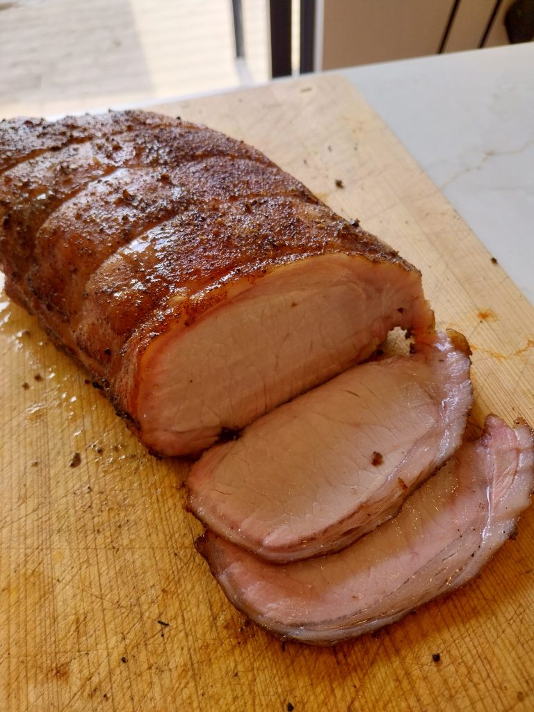 Pork loin carved on a wooden island, sliced perfect medium pink — cooked on the BGE Large at 140°C indirect