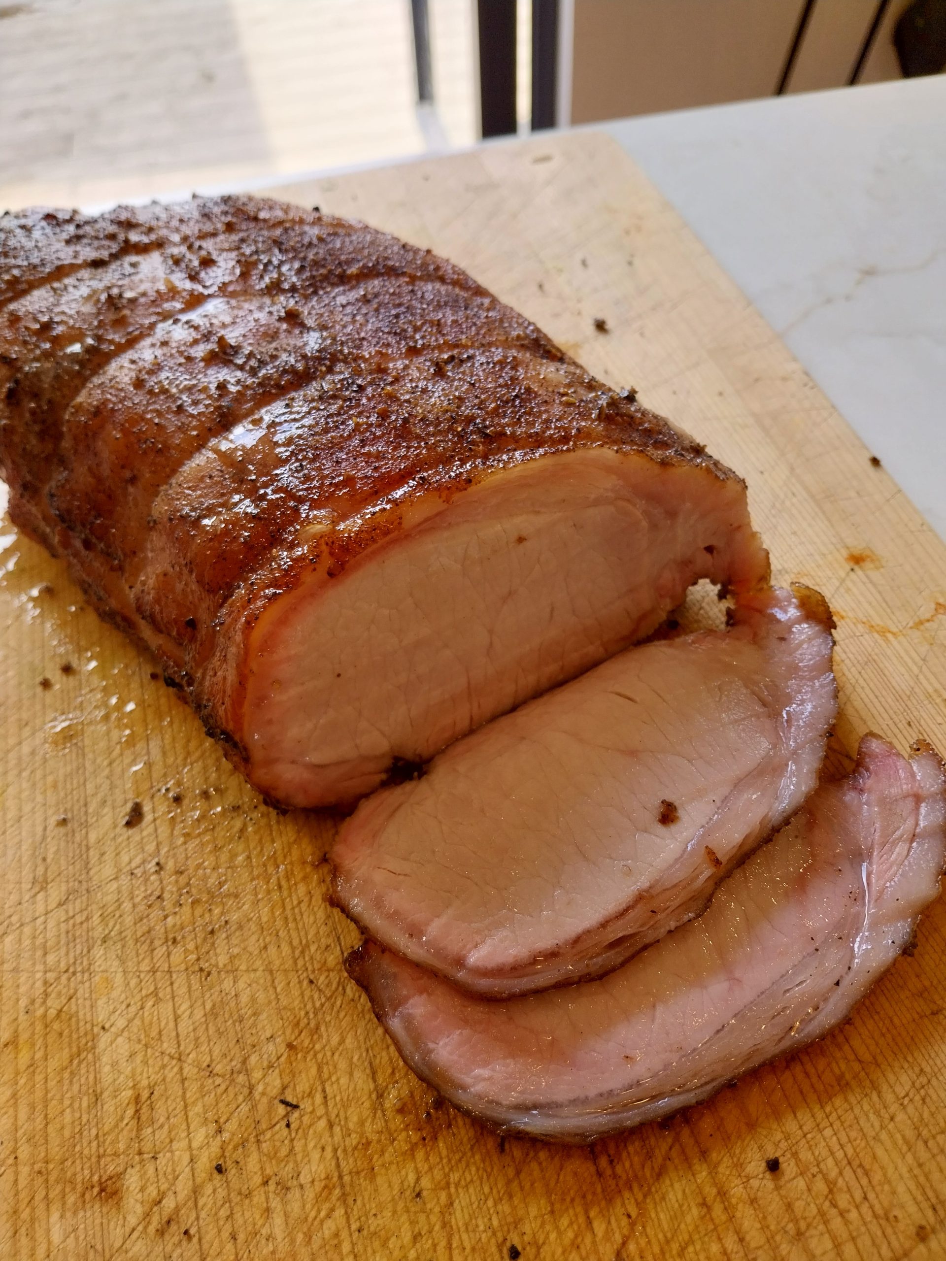 Pork loin carved on a wooden island, sliced perfect medium pink — cooked on the BGE Large at 140°C indirect