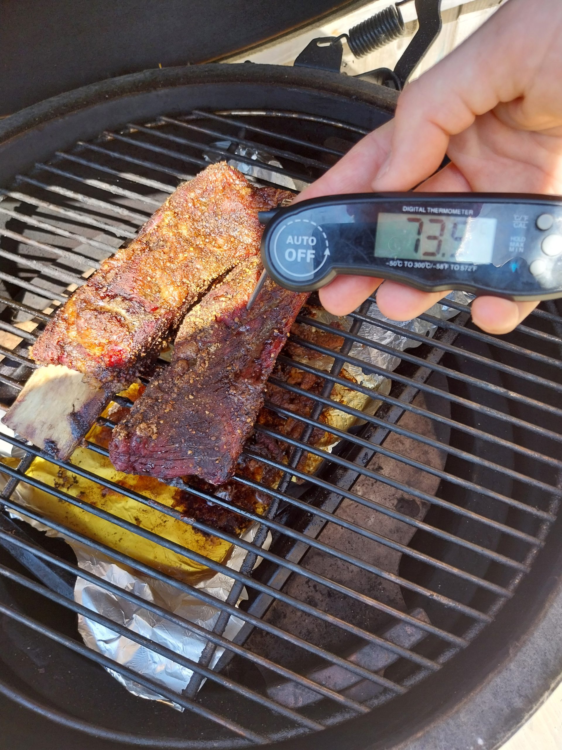 Probe reading 73°C internal on a beef short rib on the grate of the BGE Large — the wireless probe that turns a long cook from blind hoping into confident waiting