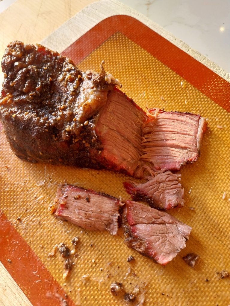 Sliced beef short rib cross-section showing bark, smoke ring, and rendered fat after a 115°C foil-wrapped cook on the BGE Large