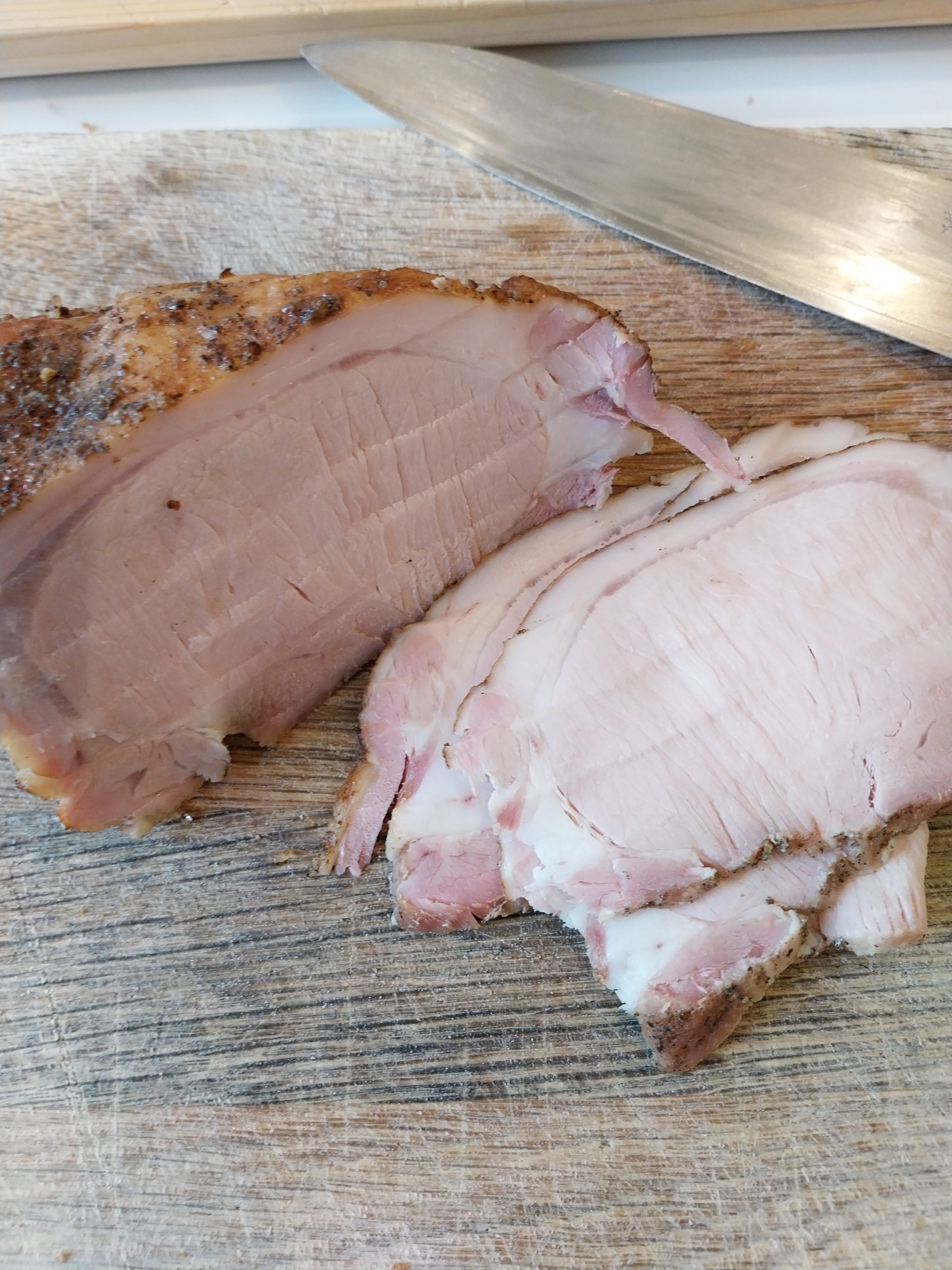 Cold pork loin slices showing a visible smoke ring — Monday-morning sandwich evidence the BGE Large held its temperature and Fuel Express produced real smoke