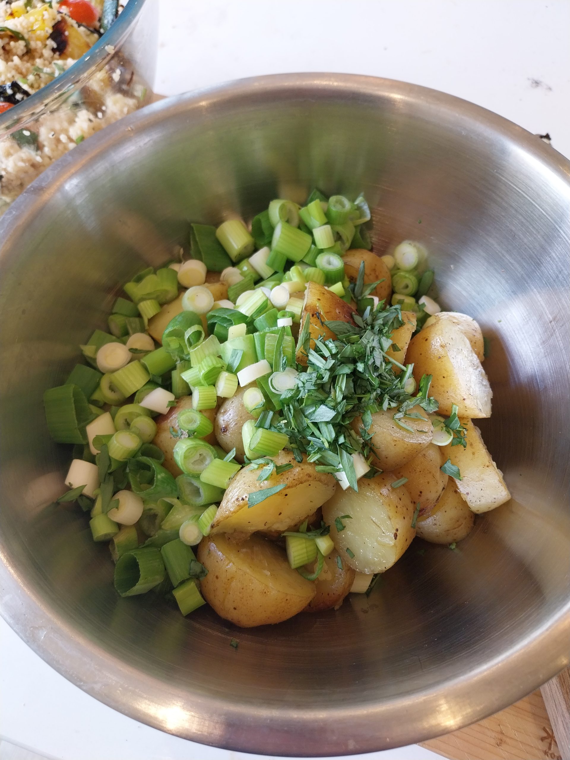 Roast potatoes folded with smoky-oil-and-confit-garlic mayonnaise, herbs and spring onions, mid-assembly