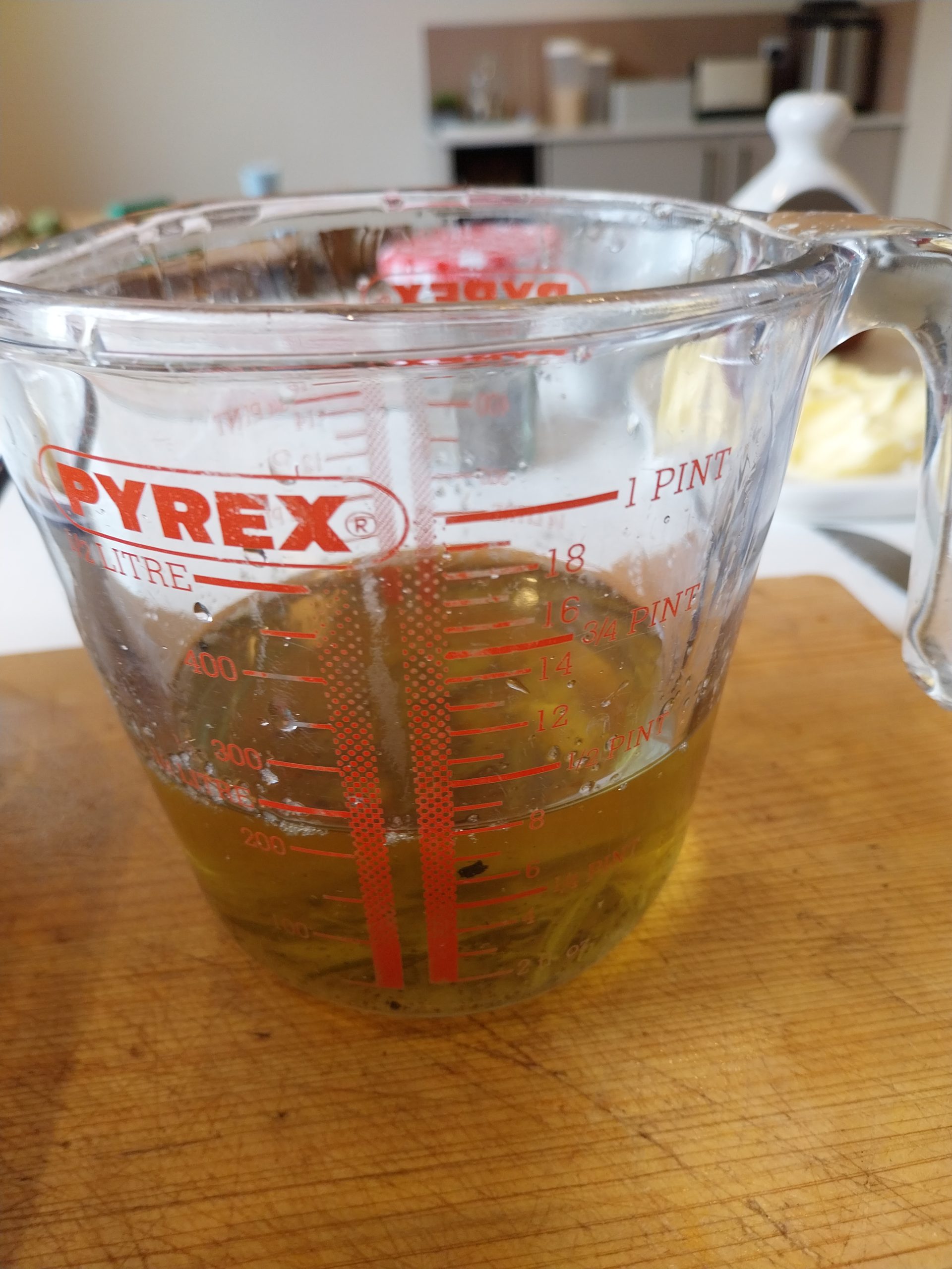 Smoky garlic-and-herb oil decanted from a foil packet into a Pyrex jug, mid-cook on the BGE Large