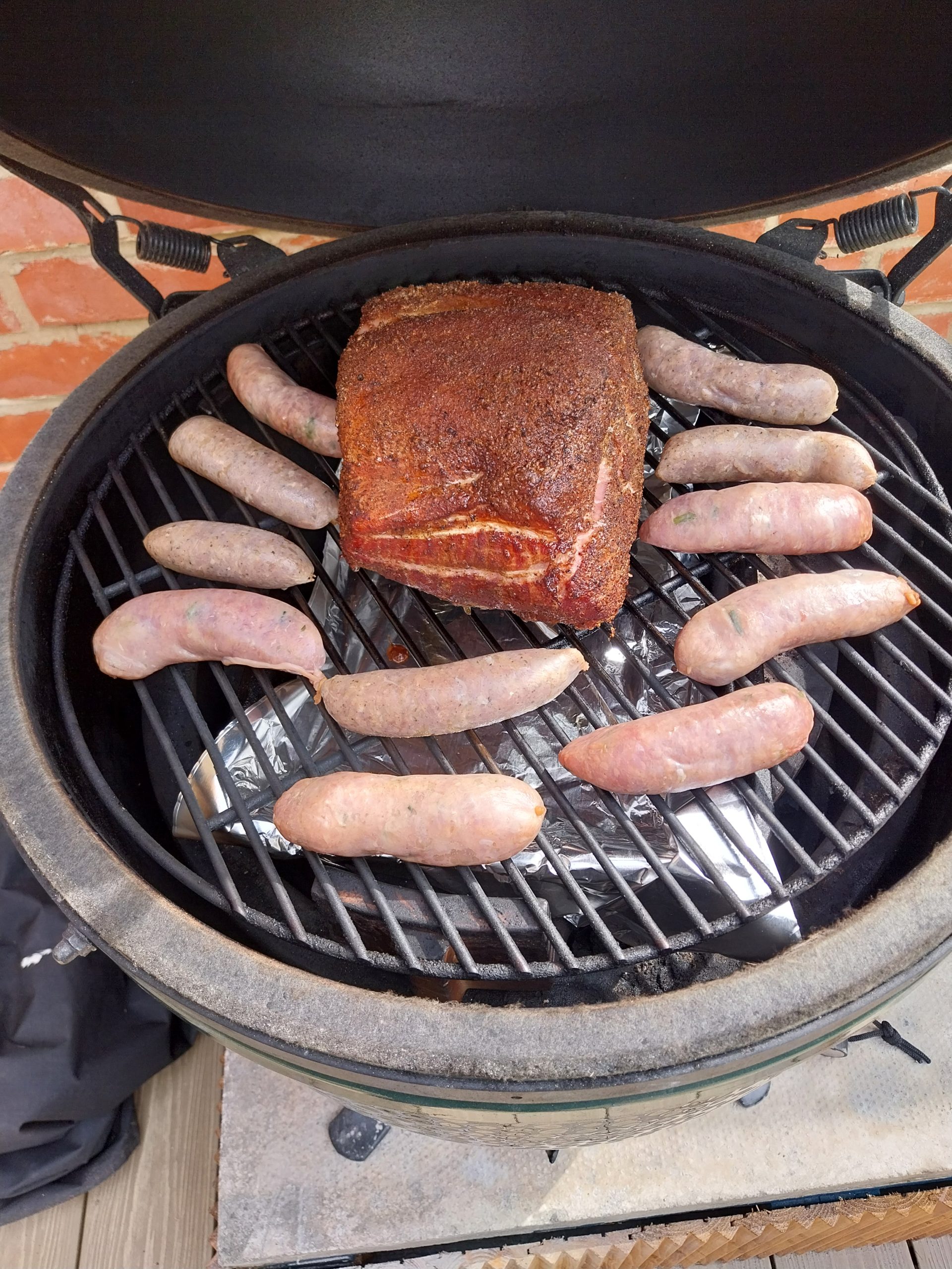 Smoked sausages on the Big Green Egg Large grate at 140°C indirect — three types from Sedum Butchers and Heck, alongside the bone-in pork loin, mid-cook on 7 June 2026.