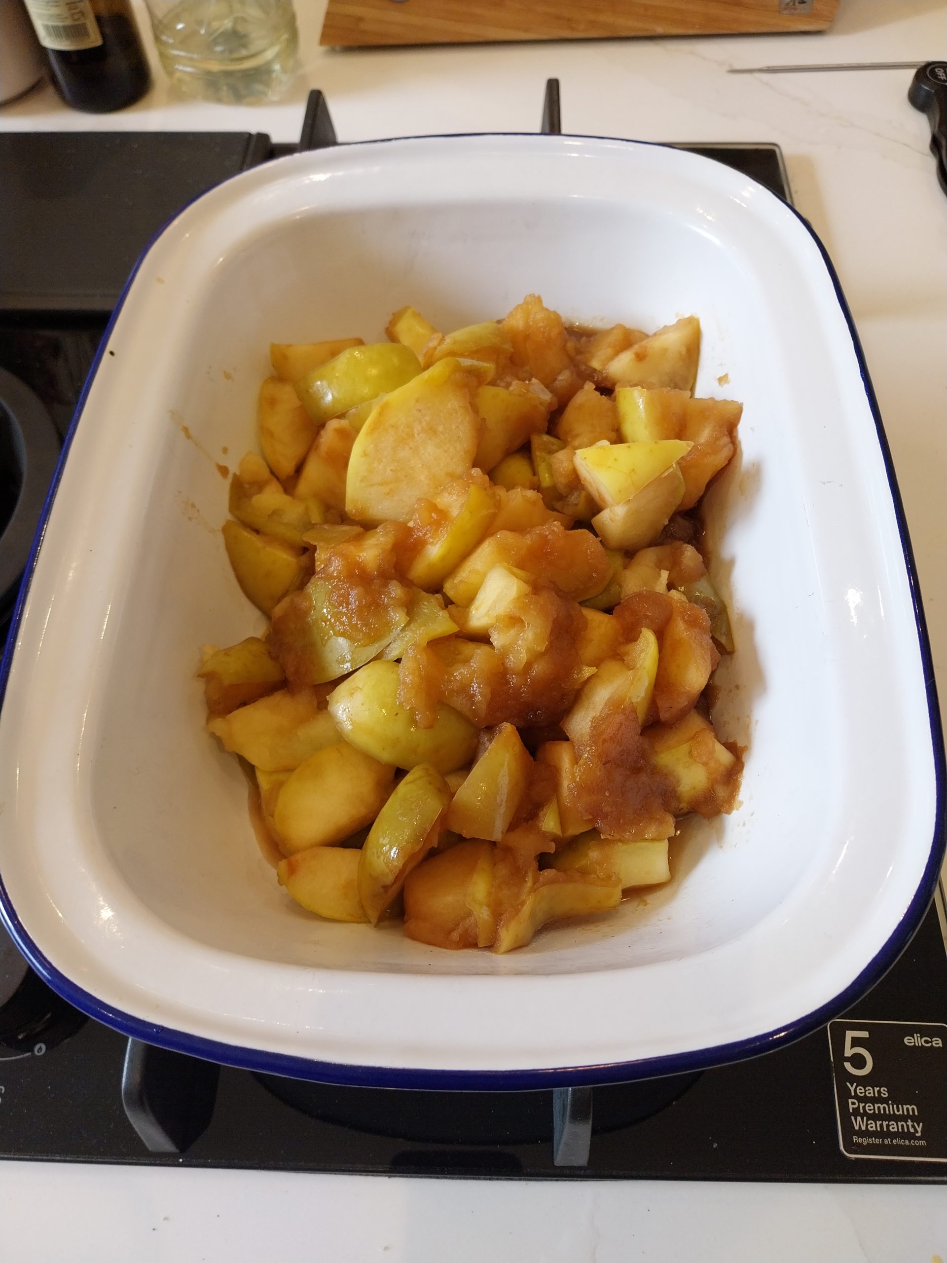 Roughly chopped cooking apples in a white dish, skins on, mid-prep before sweating down with lemon juice and sugar