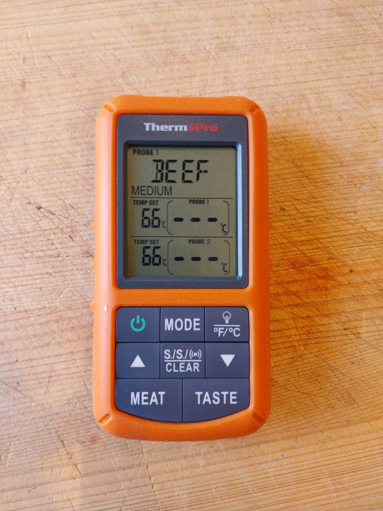 The ThermoPro TP20 receiver on a scratched wooden board, set to its beef preset, with neither probe channel showing a reading.