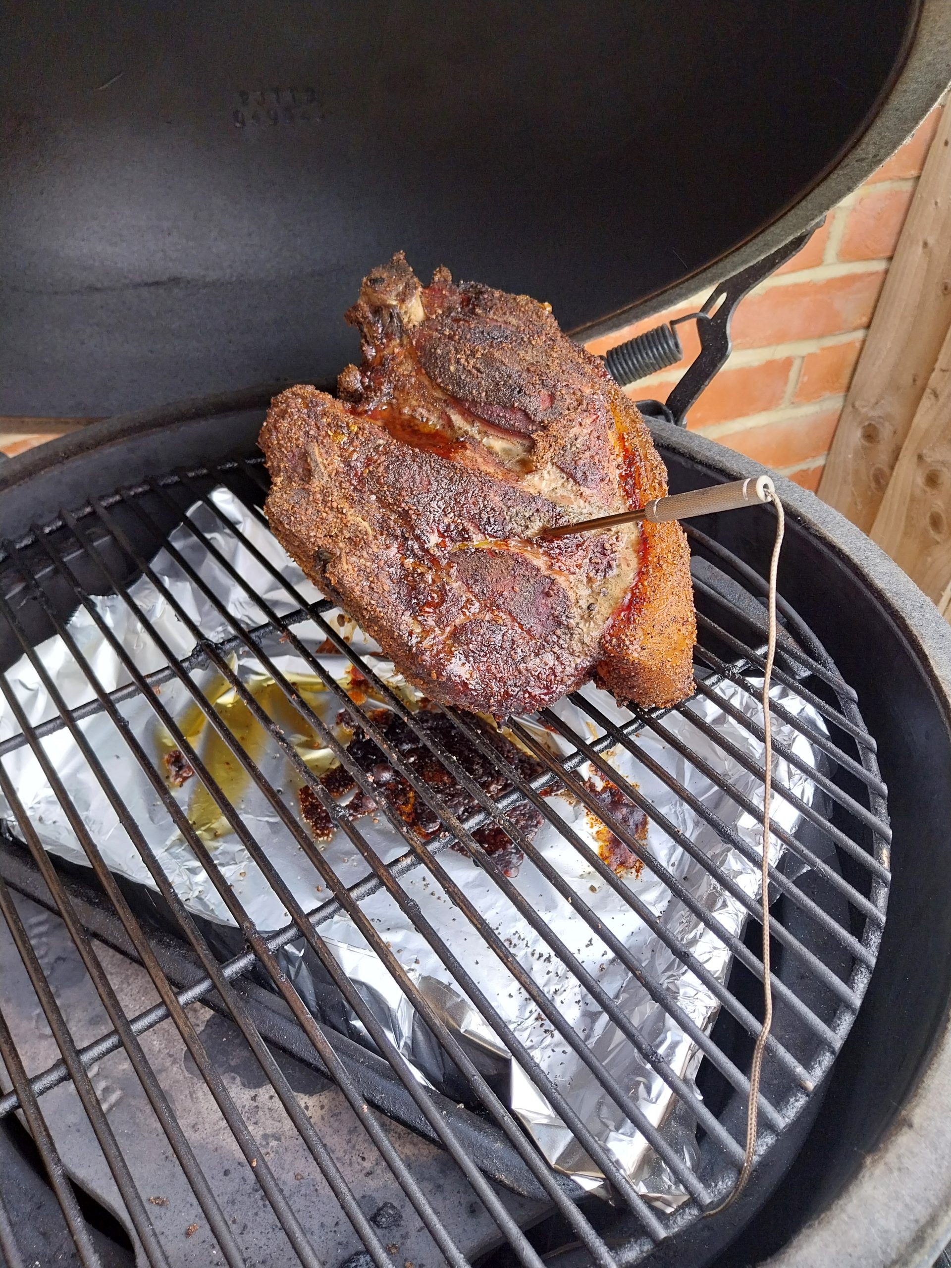 Pork shoulder mid-cook at around 19:00 BST on the BGE Large, bark fully set, internal sitting in the 77-79°C stall while collagen renders through the joint.