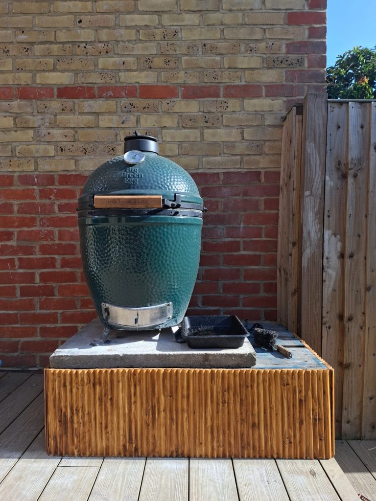The Big Green Egg Large on its base: a pallet cut in half, a paving slab on top and painted wooden trim round the edges