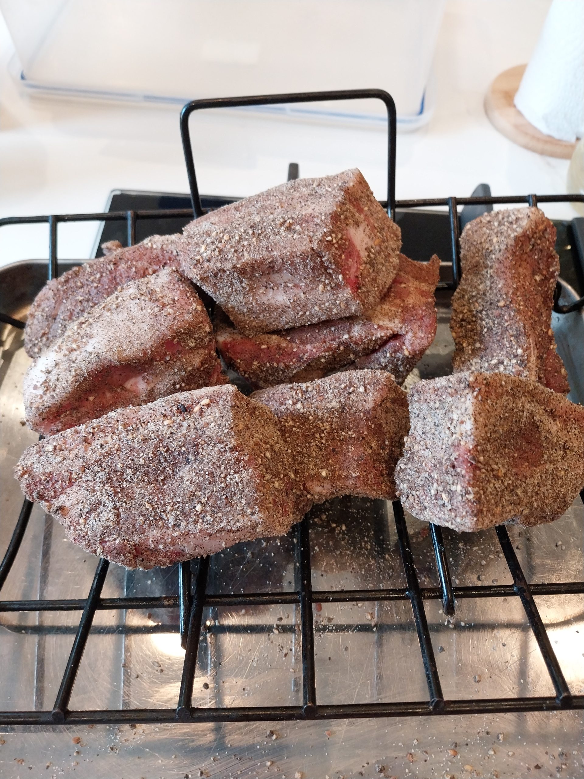 Two kilos of pork belly cubed to 3–4 cm at Leopold's Butchers, half of it rubbed with SPG-plus-Ras-el-Hanout on a rack and the rest still bare on the tray, on the morning of the cook.