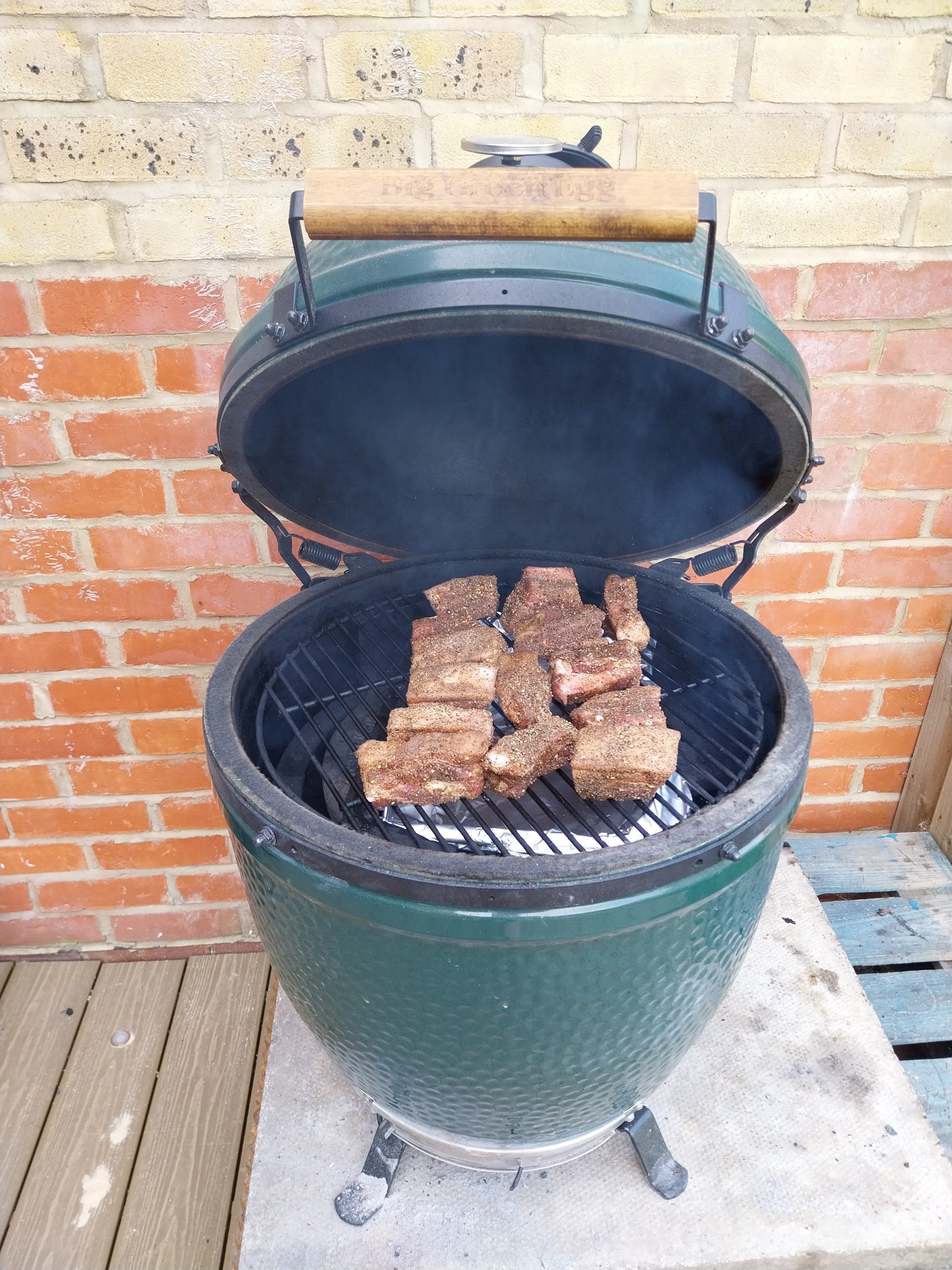Cubes spread across the grate, the SPG-plus-Ras-el-Hanout crust visible on each 3–4 cm piece, kamado at 110°C ready to hold for the next three and a half hours.