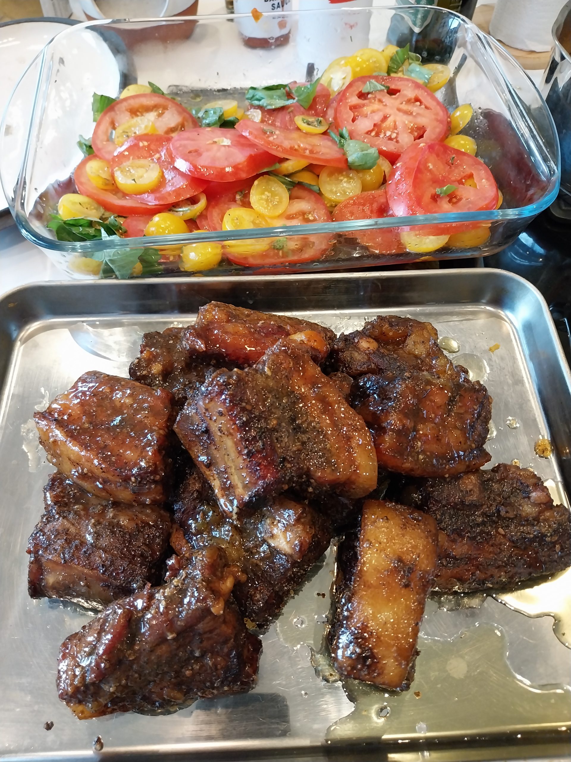 The plate five minutes after adults sat down — pork belly burnt ends alongside heritage tomato salad, quick-pickled red onions, and Middle Eastern rice with turmeric and peppers.