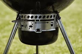 Weber Master-Touch GBS 57cm interior — the Gourmet BBQ System (GBS) cooking grate with the hinged fuel-access section flipped up for adding charcoal mid-cook.
