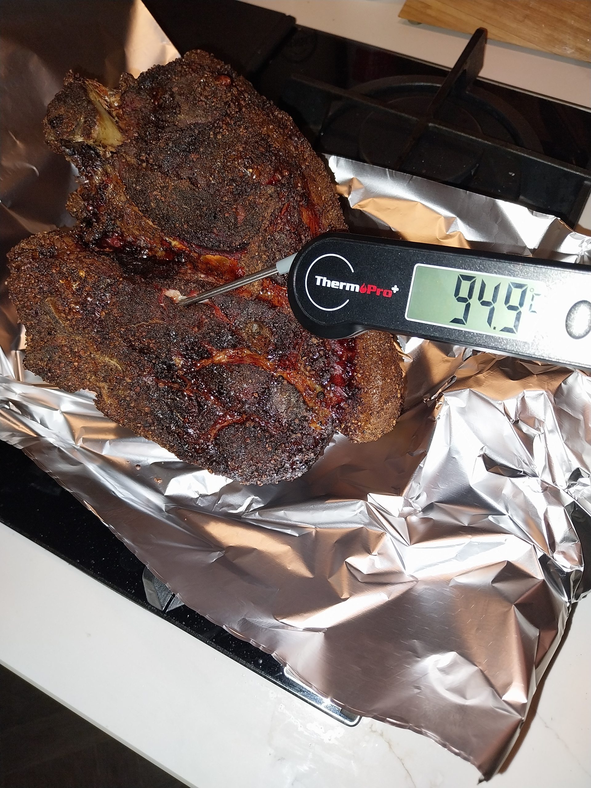 Pork shoulder on the BGE Large grate around 22:26 BST — leave-in probe registering 92°C, checking the probe-tender feel with an instant-read before pulling the joint off the kamado.