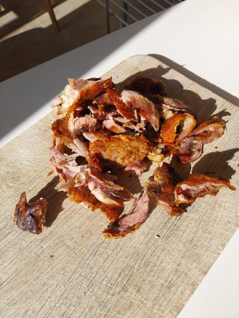 Duck legs cooked in oil on the kamado, shredded off the bone on a wooden board, crisp skin mixed through the meat