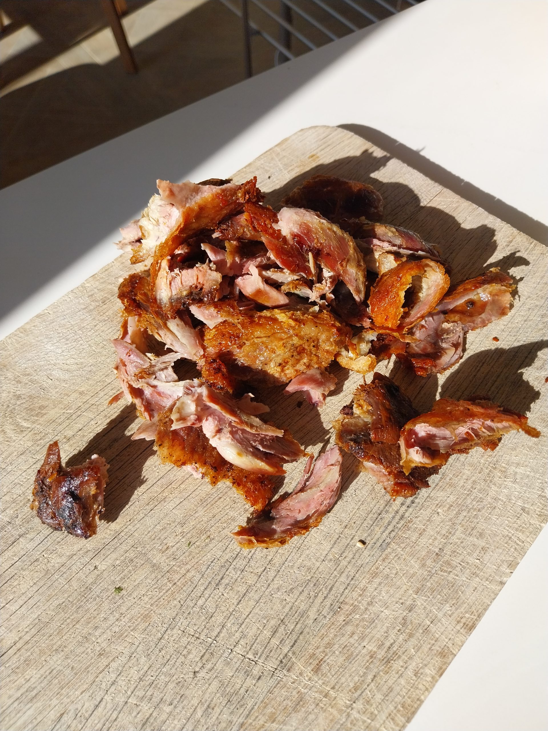 Duck legs cooked in oil on the kamado, shredded off the bone on a wooden board, crisp skin mixed through the meat