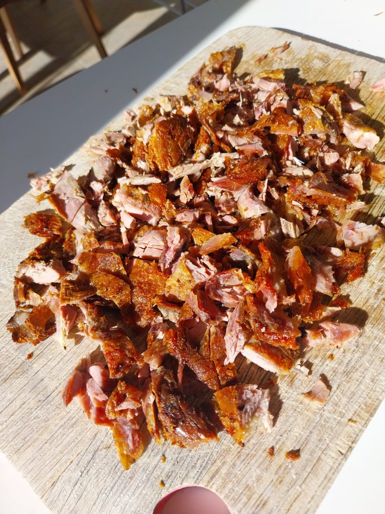 The shredded duck chopped down small, spread across the board ready for wraps