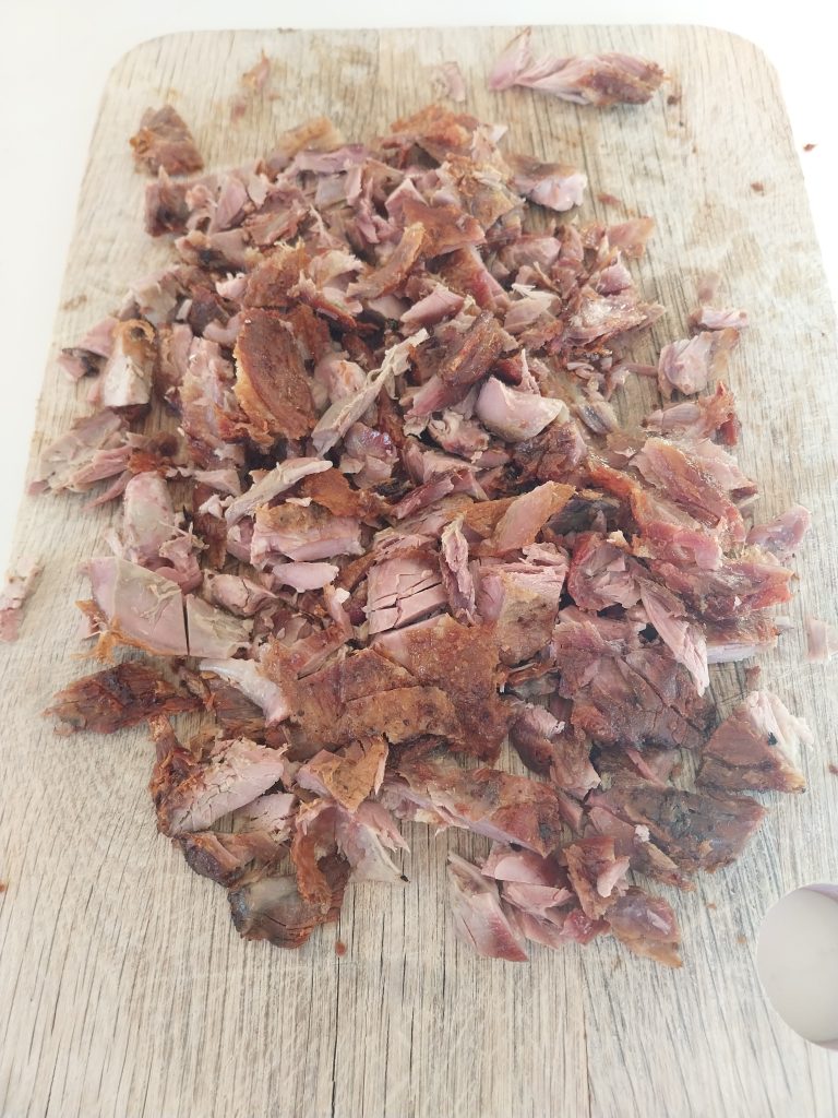 The shredded duck chopped down small, spread across the board ready for wraps