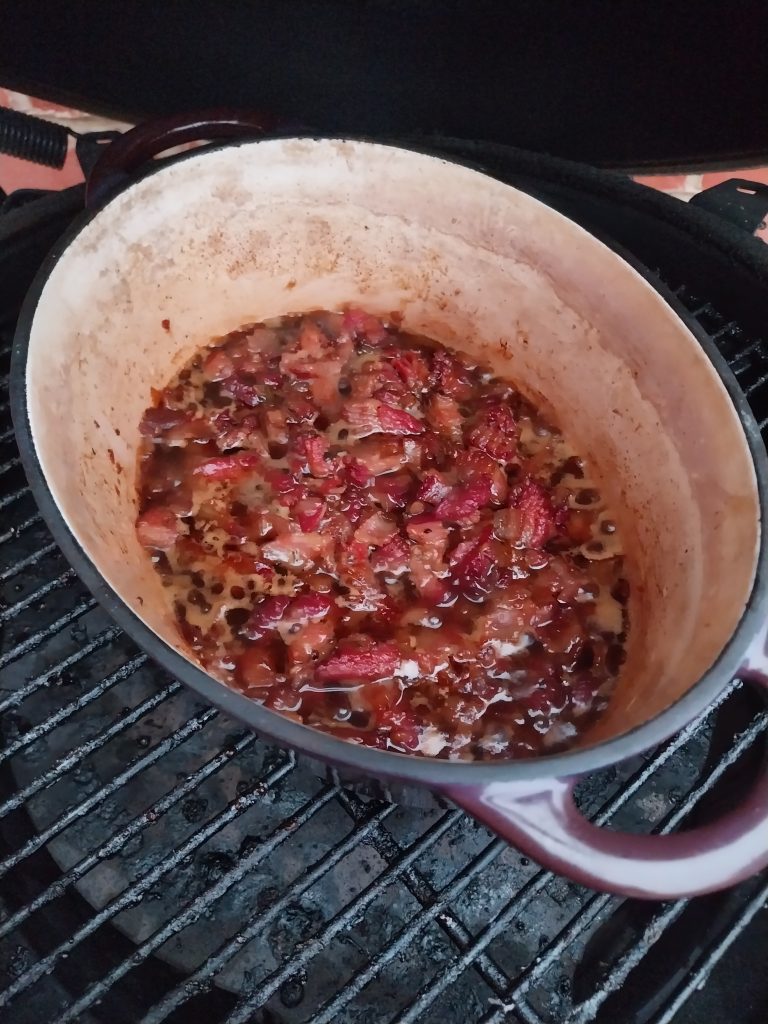 Bacon jam in a cast iron pot on the kamado grate, cooked down and about to come off