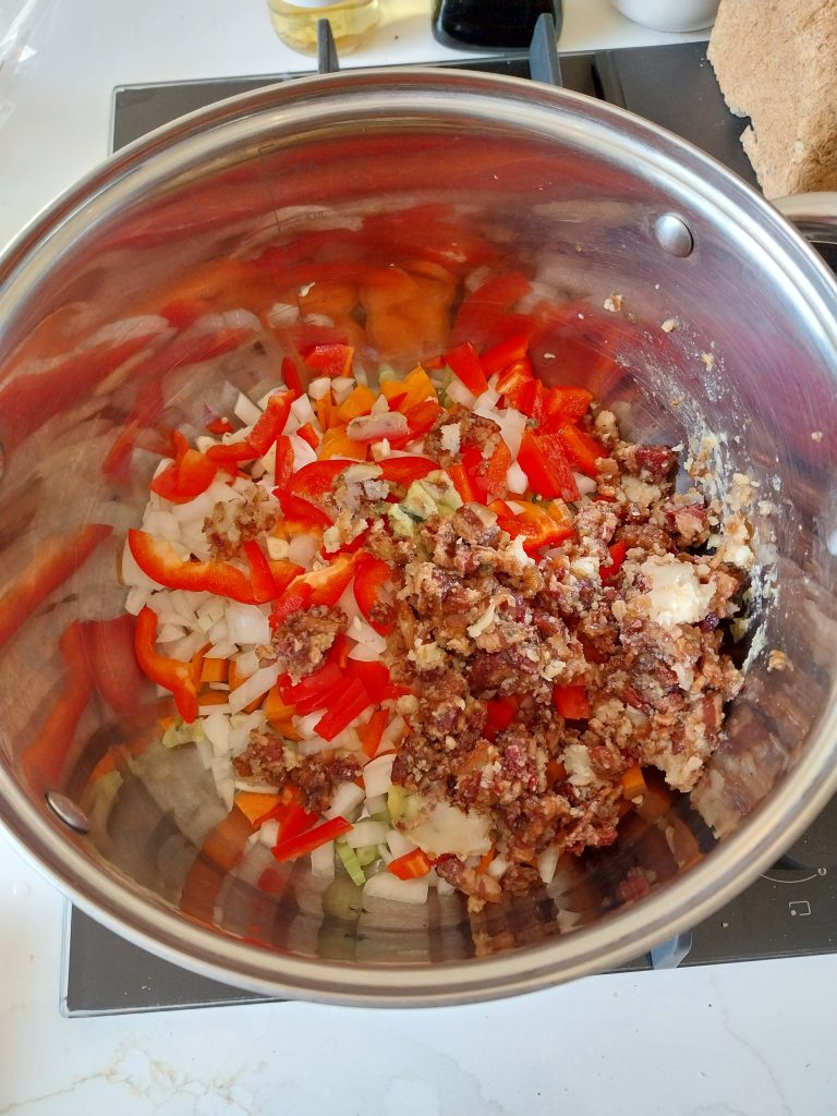 The chilli base assembled raw in a stainless steel pan on the kitchen worktop, chopped peppers, onion, carrot and celery with bacon jam sitting on top, before it went out to the barbecue.
