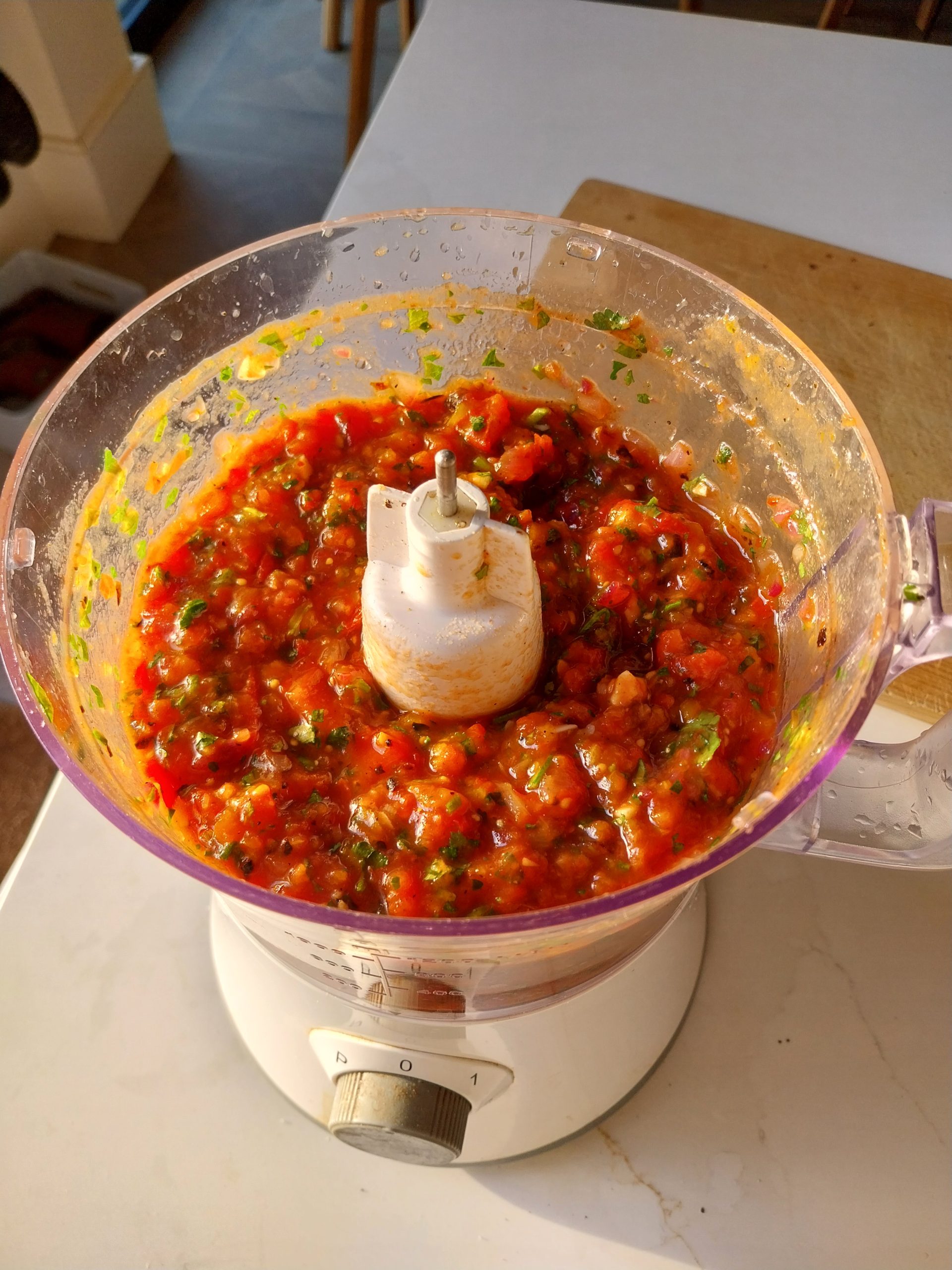 The finished charred tomato salsa in the bowl of a food processor, coarsely blitzed with coriander and flecks of char through it