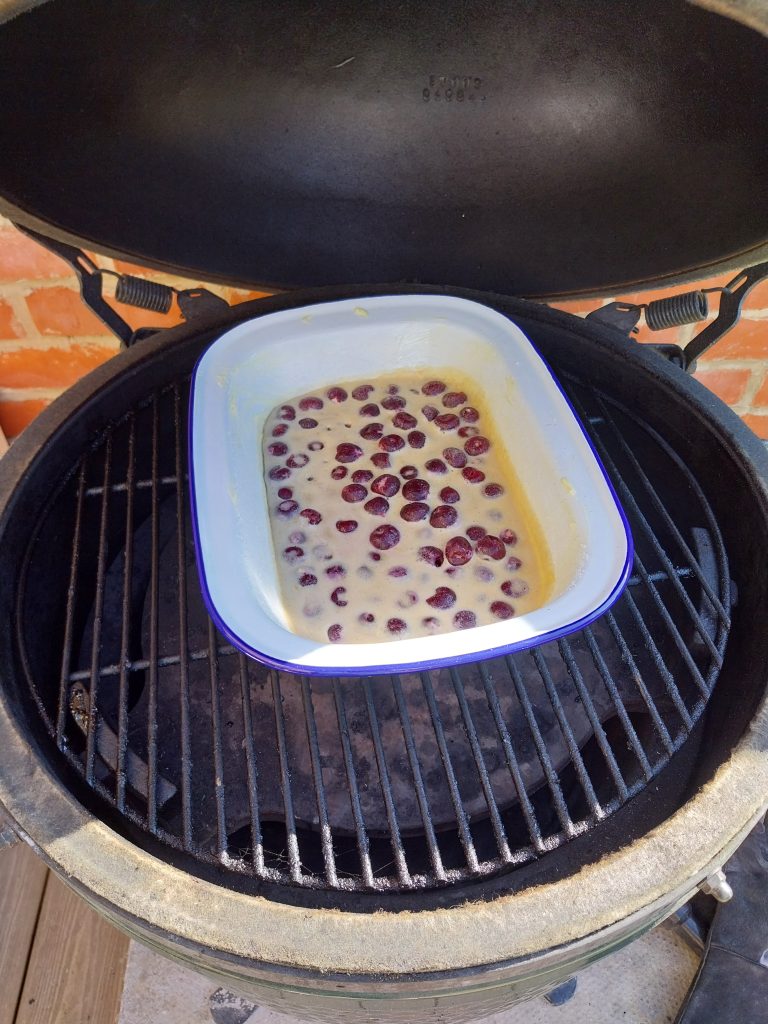 The dish of batter and cherries going onto the grid of the Big Green Egg