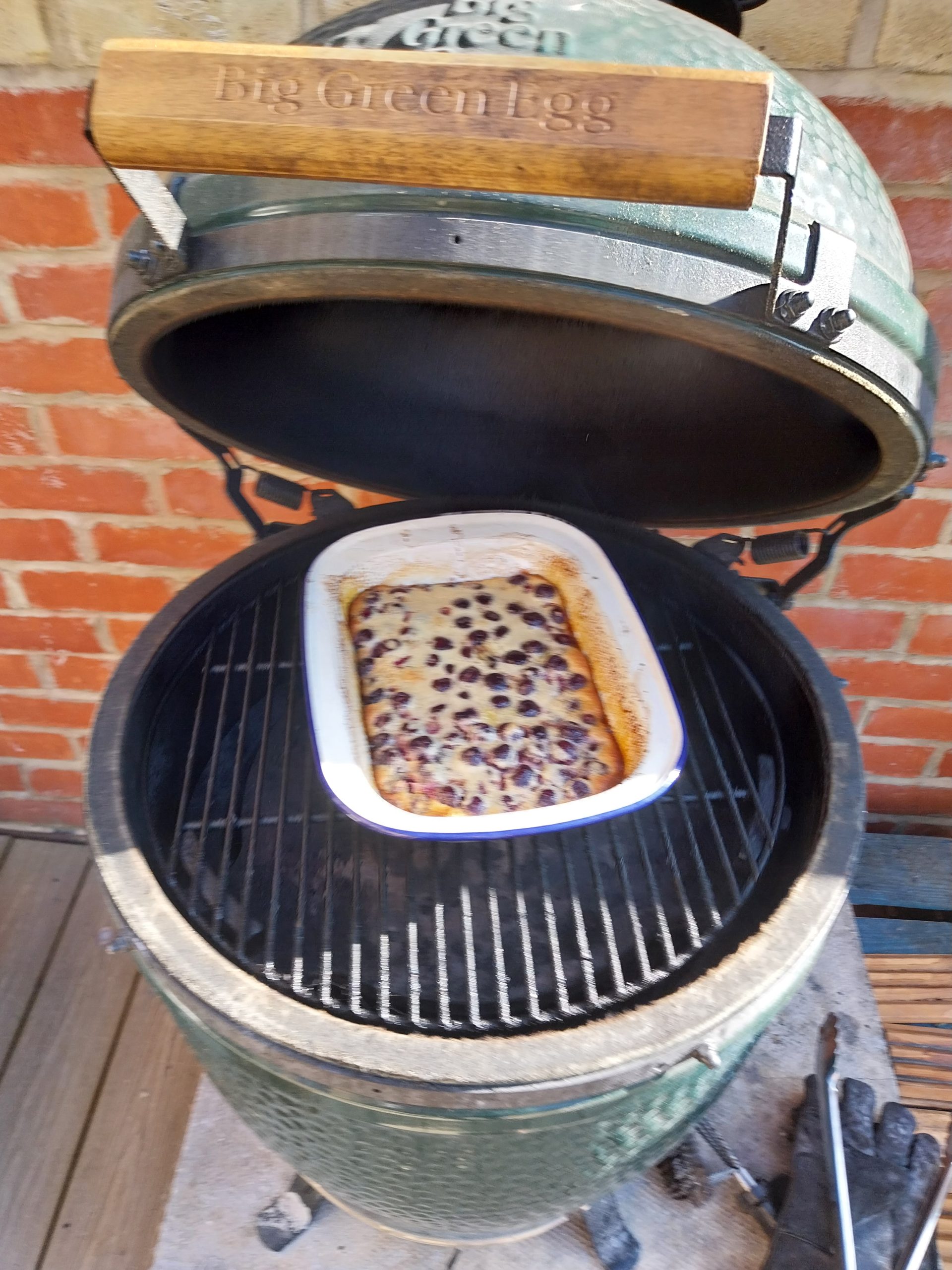 The clafoutis risen and puffed up above the rim of the dish while still on the barbecue