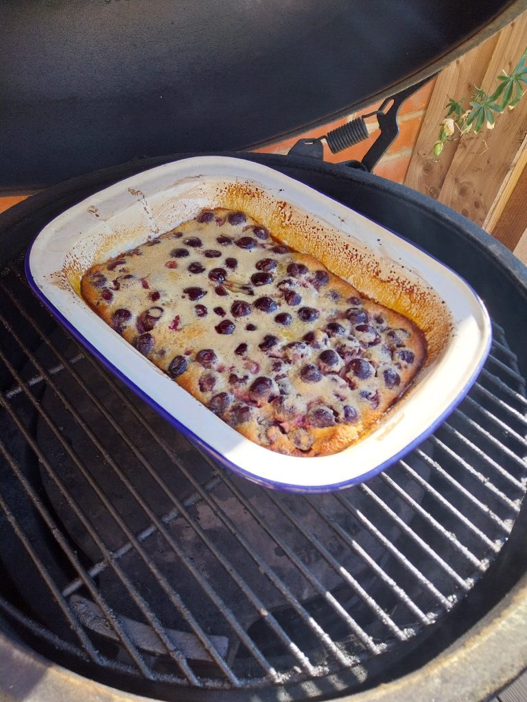 The cherry clafoutis rising in its dish on the grid of the Big Green Egg.