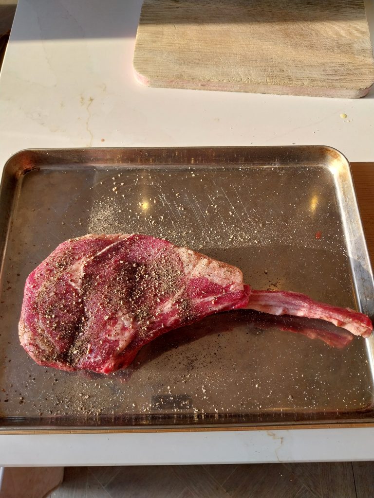 The bone-in tomahawk seasoned with salt and pepper before it went on
