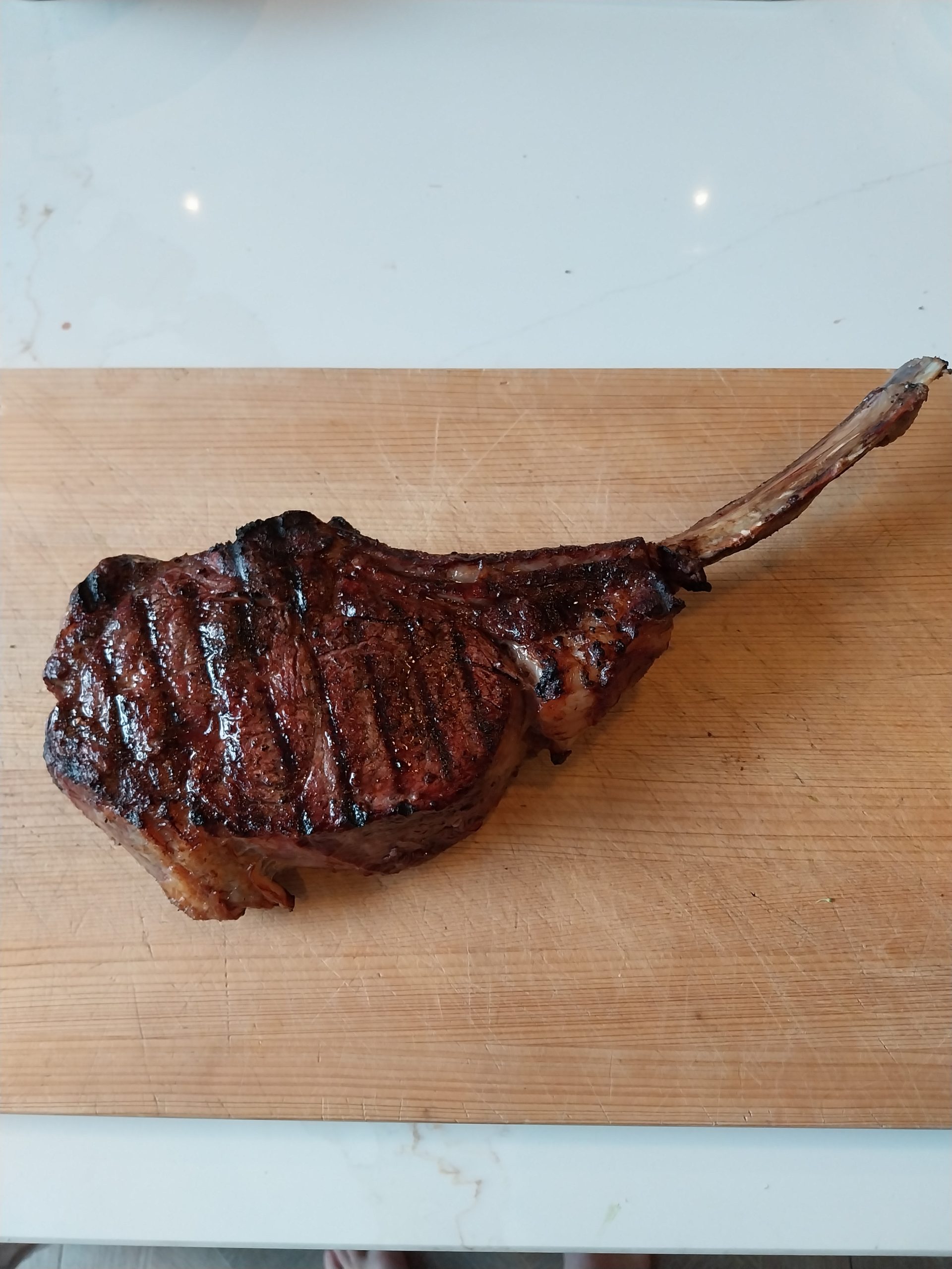 The tomahawk resting on a wooden board after the sear