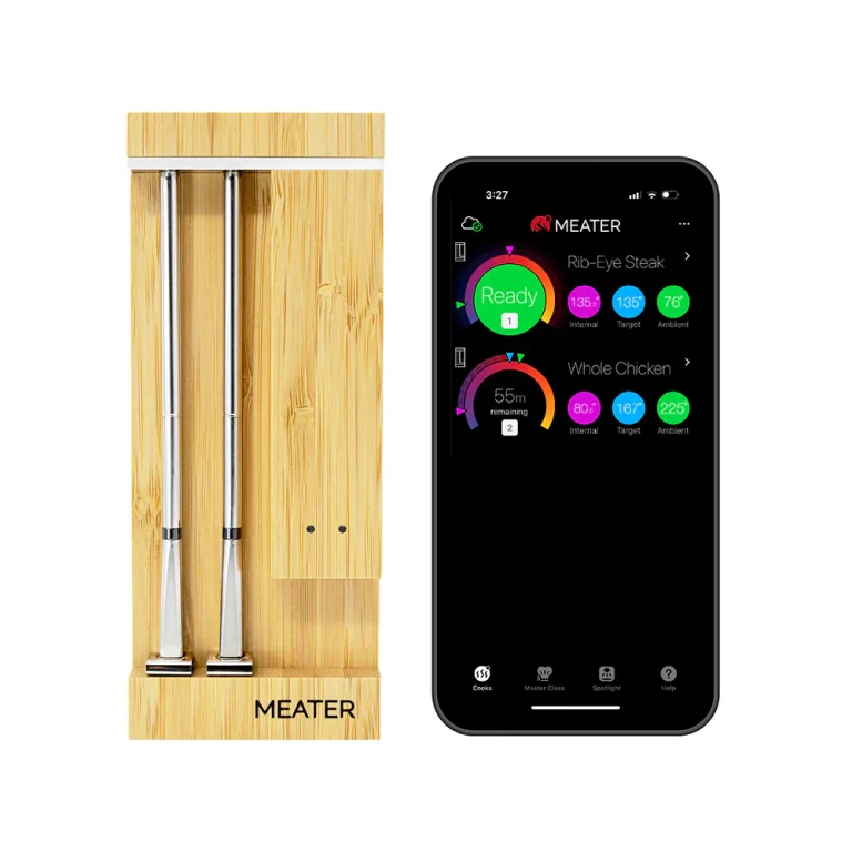 MEATER Pro Duo — two stainless probes in the bamboo charging block, beside a phone running the MEATER app with two cooks on screen. Image: MEATER UK.