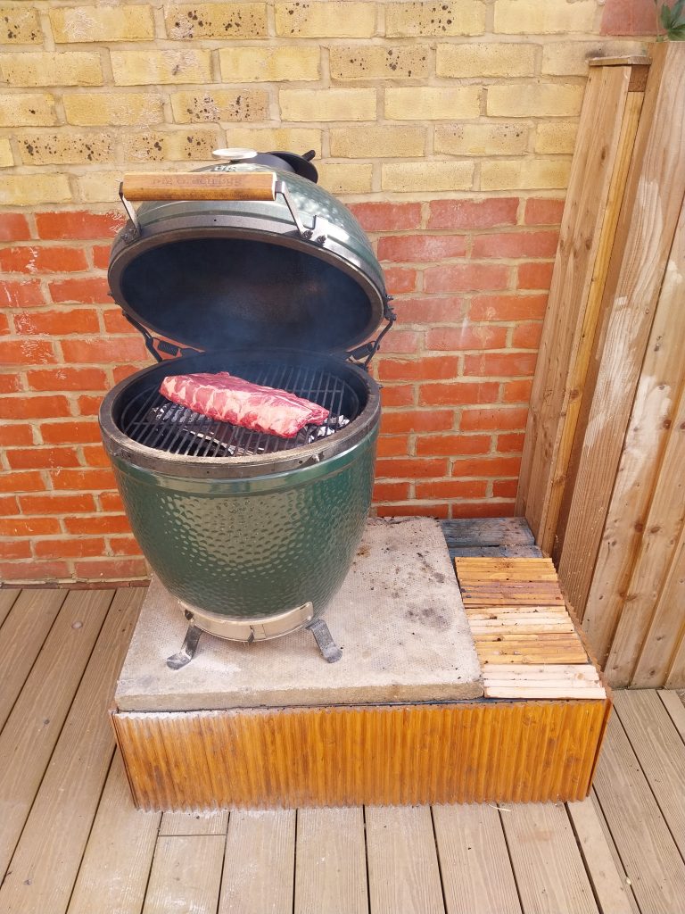 The rack of baby back ribs going onto the Big Green Egg, lid open.