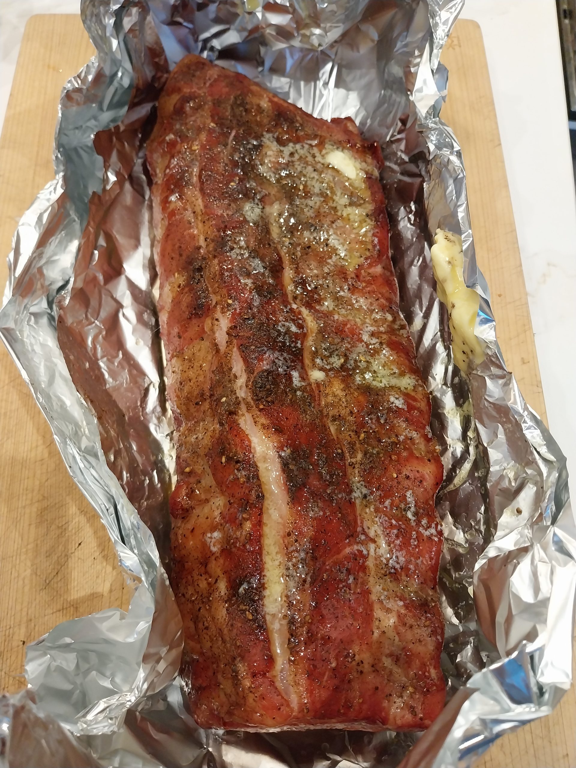 The rack on an open sheet of foil ready to wrap, a knob of butter beside it and more already melting across the top