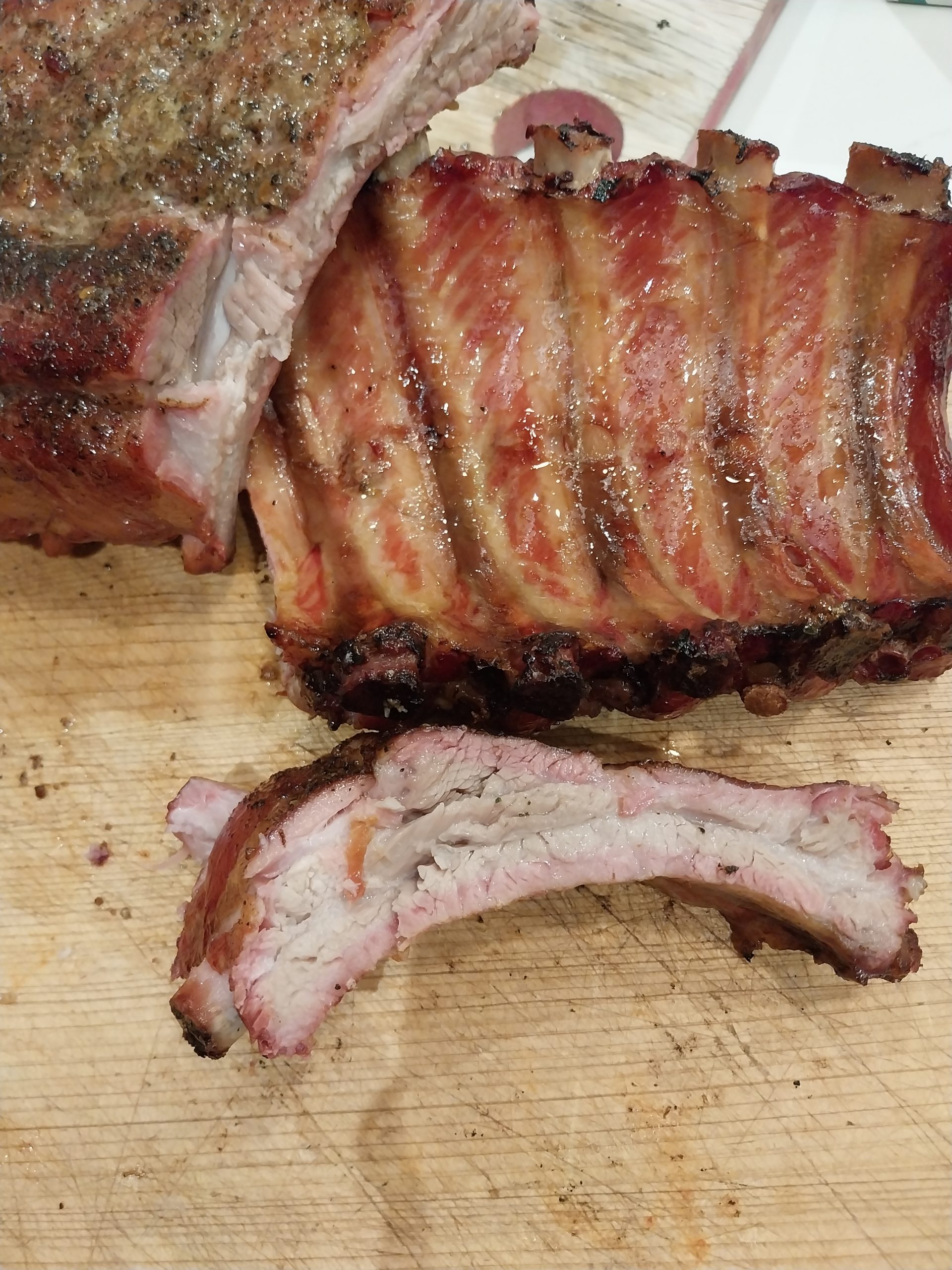 A single rib carved off the rack, the cut face showing a pink smoke ring under the dark edge