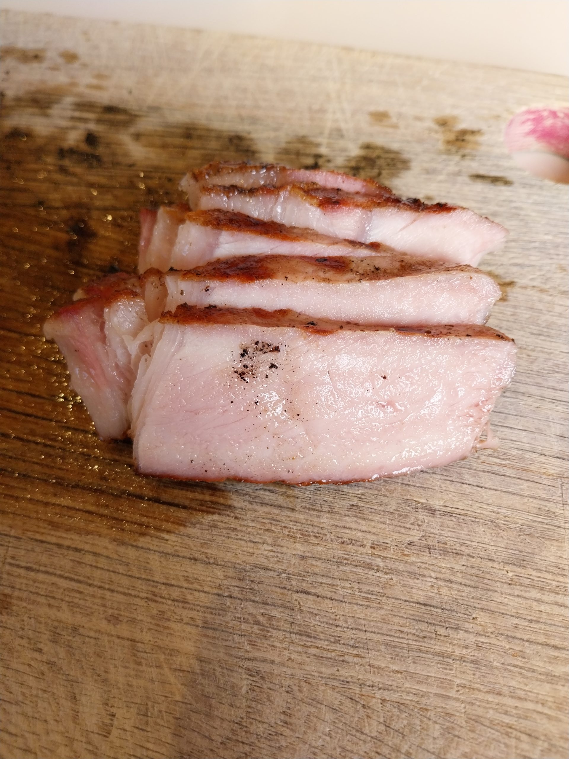 Slices of the pork chop on a board, pink in the middle