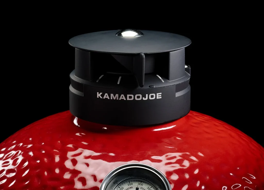 Kamado Joe Classic III — close-up of the black Kontrol Tower top vent on the red dome, with the dome thermometer below it. Image: Kamado Joe.