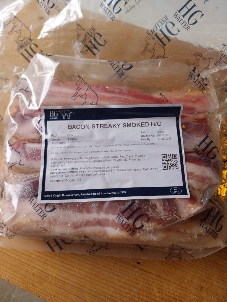 A vacuum pack of HG Walter smoked streaky bacon on a wooden worktop, label reading BACON STREAKY SMOKED H/C.