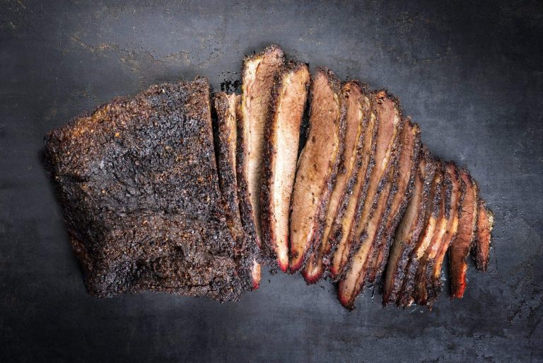 A smoked brisket sliced on a dark board, from Bromfields' packer cut listing.