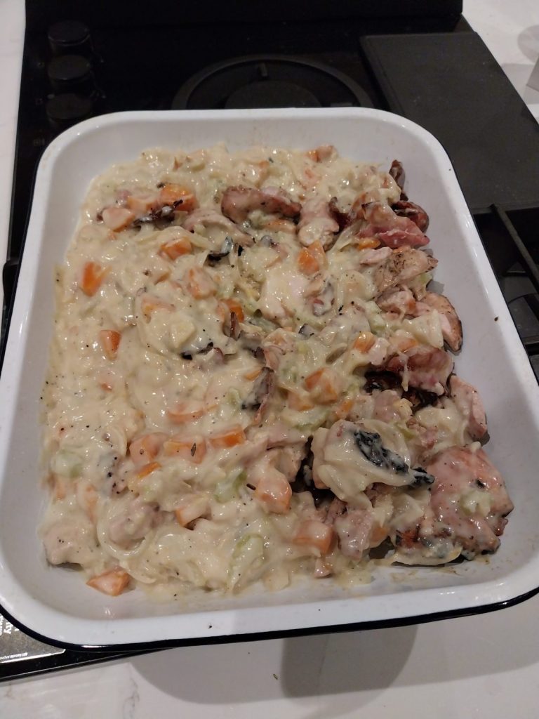 Chicken, bacon, carrot, celery and onion in a white sauce in an enamel dish, before the pastry goes on