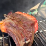 A thick bone-in rib steak cooking on a barbecue grill, from Field & Flower's website.