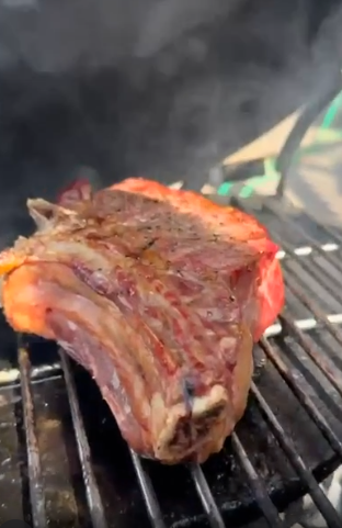 A thick bone-in rib steak cooking on a barbecue grill, from Field & Flower's website.