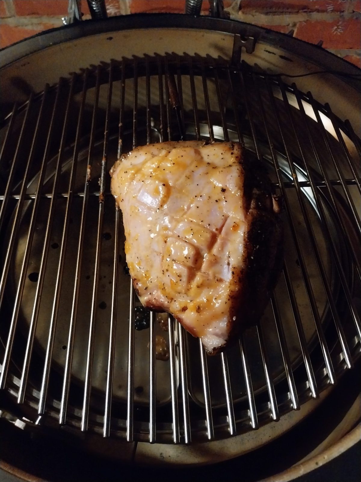 A gammon joint with the rind off, the fat scored and glazed, on a barbecue grid
