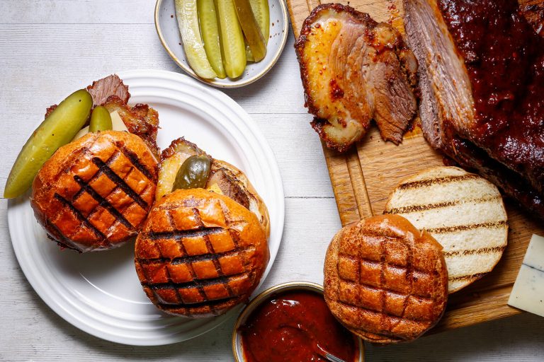 Sliced smoked brisket in toasted buns with pickles, from HG Walter's brisket listing.