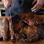 A smoked brisket being sliced on a wooden board, from Swaledale's brisket listing.