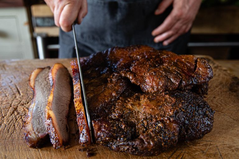 A smoked brisket being sliced on a wooden board, from Swaledale's brisket listing.