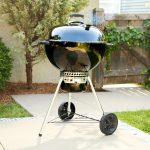 A black Weber Master-Touch GBS with the lid on, standing on a patio